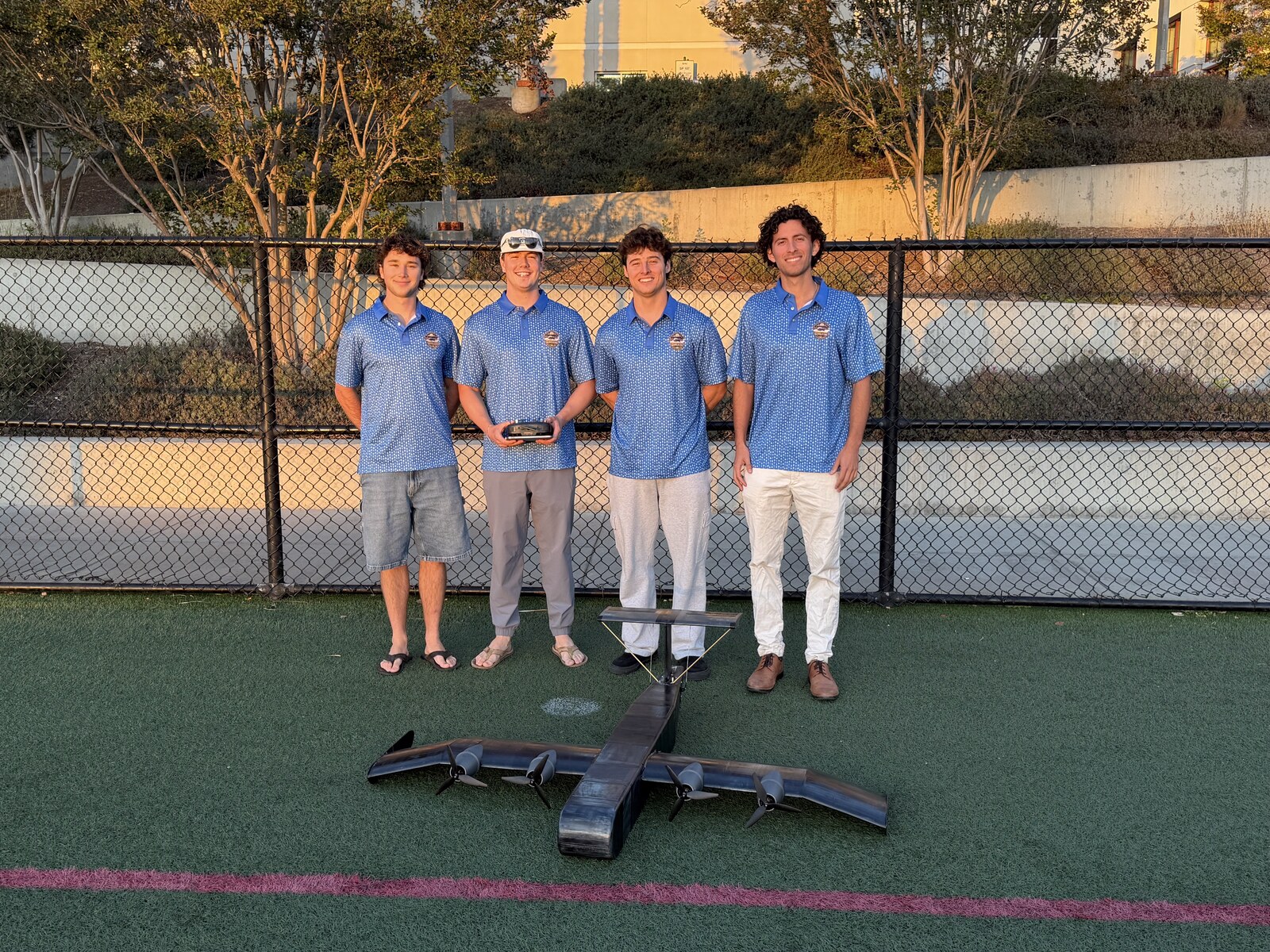 The team standing behind the WIG vehicle on the practice field at golden hour during Flight Test 4.